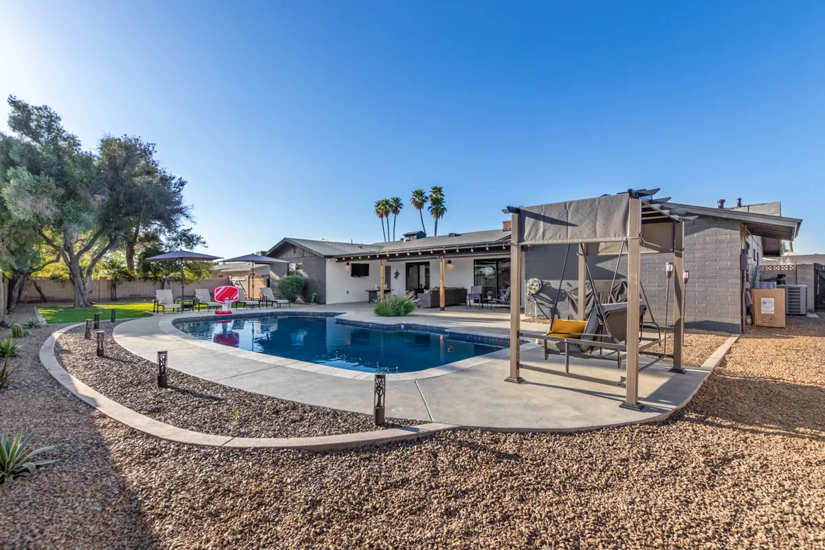 This image displays a sparkling swimming pool surrounded by an inviting outdoor seating area, lush palm trees, and a spacious covered patio. The scene exudes a sense of resort-style relaxation, with comfortable loungers and shaded spots perfect for unwinding or brainstorming outdoors.
