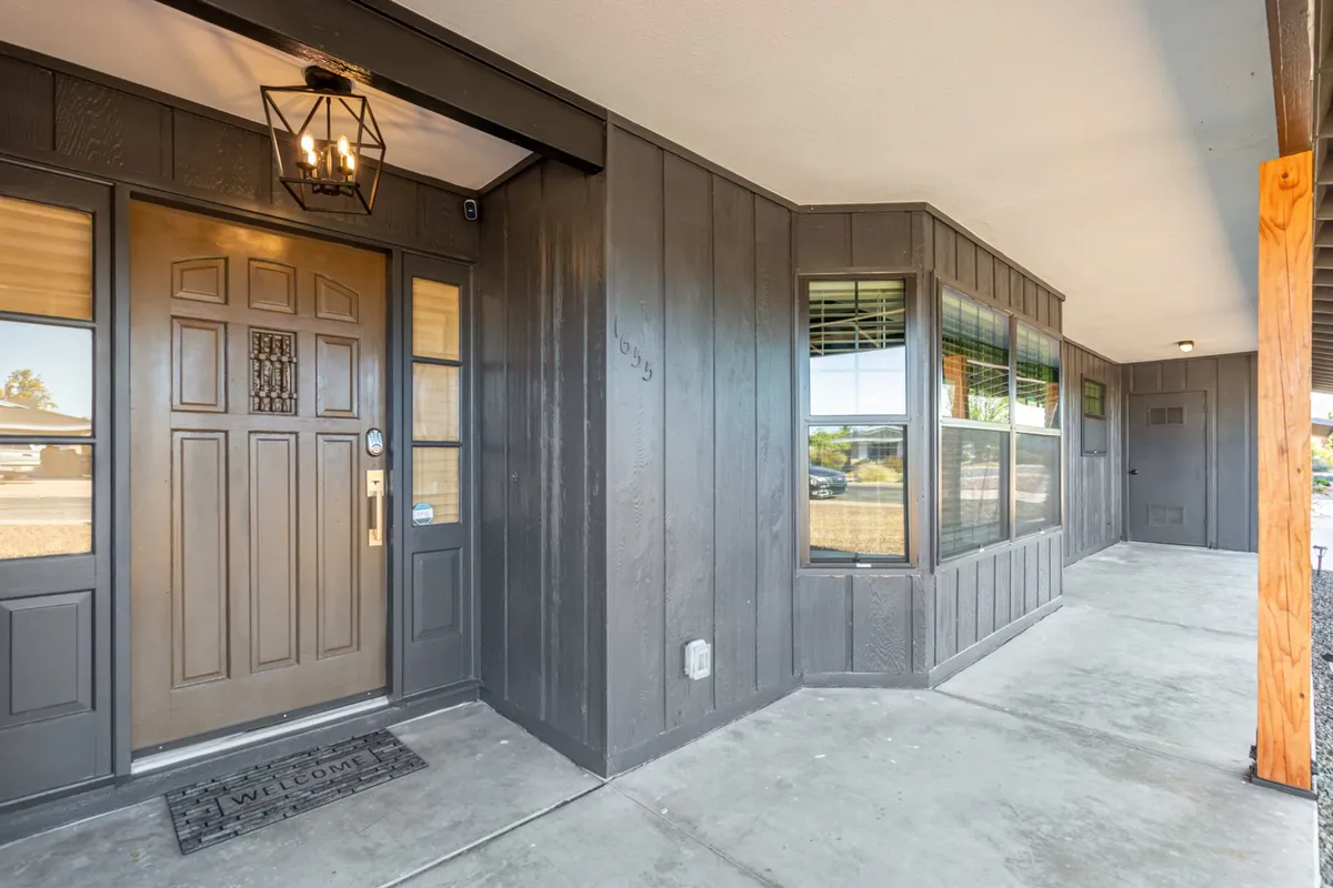 The warm and welcoming front door of the property, illuminated by an overhead light and framed by windows, sets a positive first impression. The porch area invites guests to enjoy the view or step inside to discover the versatile living spaces.