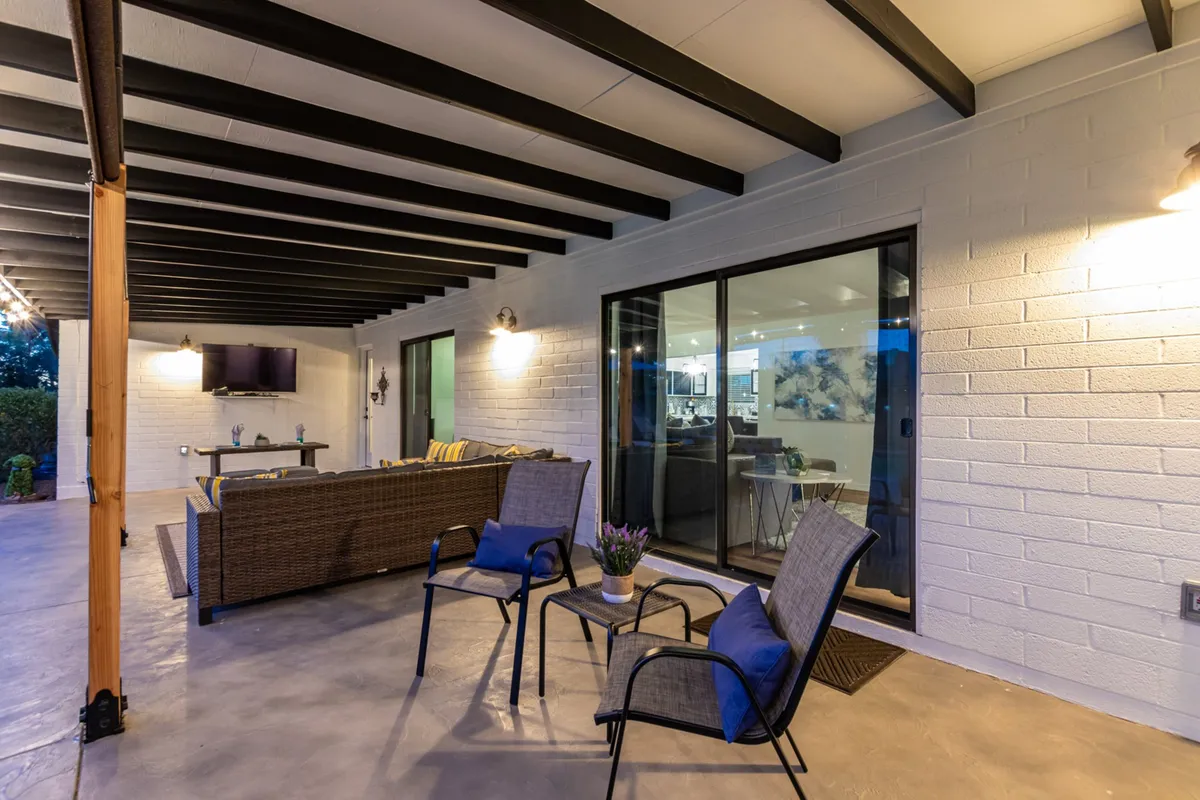 An outdoor seating area with decorative lighting and glass sliding doors, offering a cozy spot for dining, socializing, or simply relaxing with friends. The setup is both stylish and functional, suggesting evenings filled with laughter and shared moments.