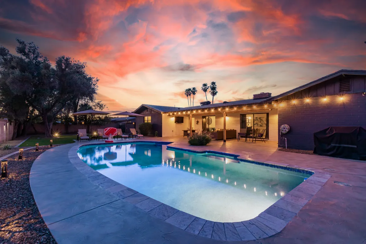 This image features an inviting swimming pool surrounded by comfortable outdoor seating, palm trees, and decorative lights. The serene ambiance suggests relaxation and the perfect setting for social gatherings or tranquil evenings under the stars.
