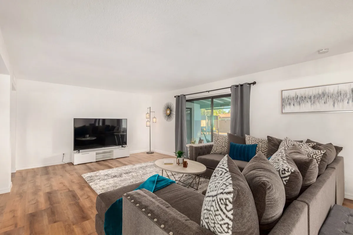 A cozy family room with a large television, comfortable sofa, decorative pillows, a coffee table, and a window view. The arrangement invites relaxation, movie marathons, and family gatherings, matching the atmosphere of friendly competitions and shared leisure.