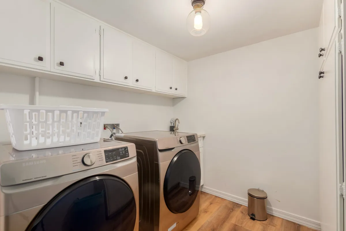 A tidy laundry room featuring a washing machine, dryer, and laundry basket. The space is thoughtfully organized, highlighting its practicality and ease of use for extended stays.